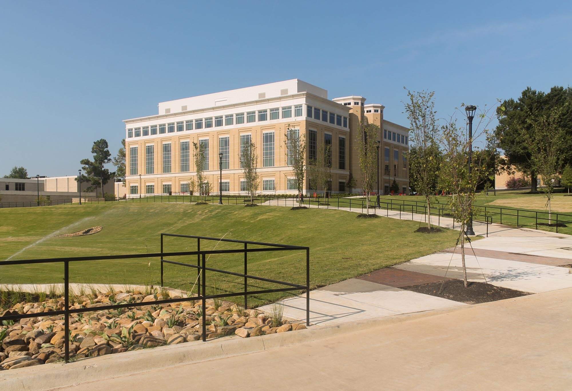 Multi-story humanities building with tan brick exterior, vertical windows and landscaped grounds