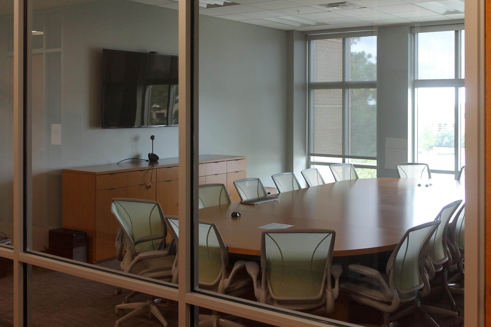 Conference room featuring an oval table surrounded by mesh chairs