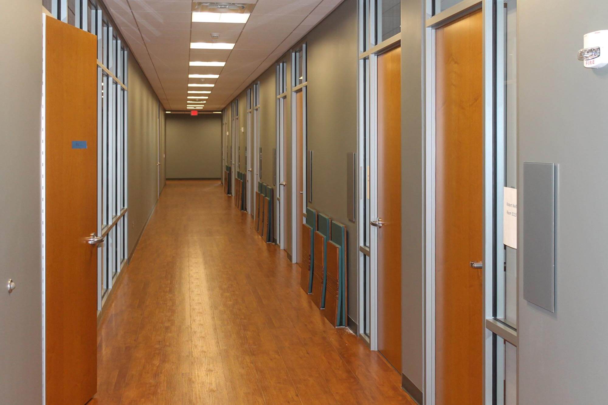 Hallway with glass-partitioned offices and wood floors