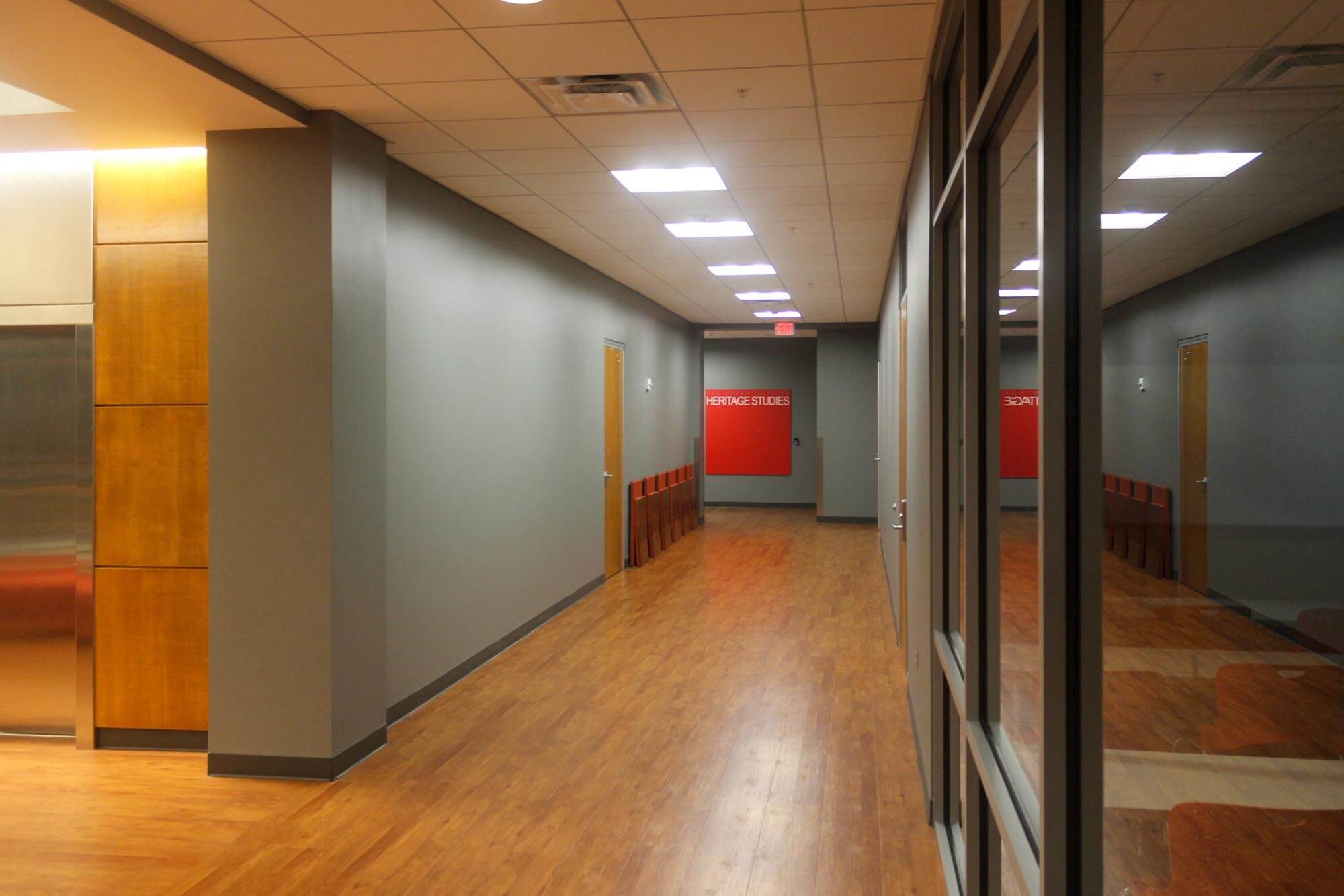 Corridor with wood flooring and red signage for “Heritage Studies”