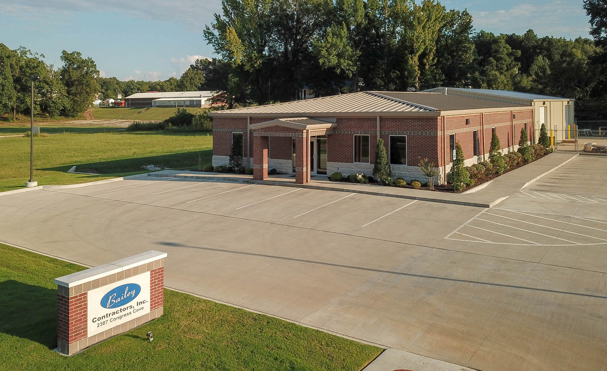 Aerial exterior shot of the Bailey Contractors, Inc. office building, featuring a single-story brick structure with a covered entrance, large windows, and a metal roof
