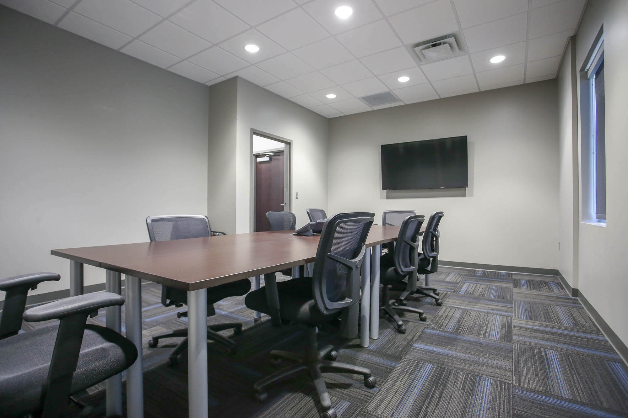 Interior shot of the conference room at Bailey Contractors, Inc., featuring a long rectangular meeting table surrounded by black mesh office chairs