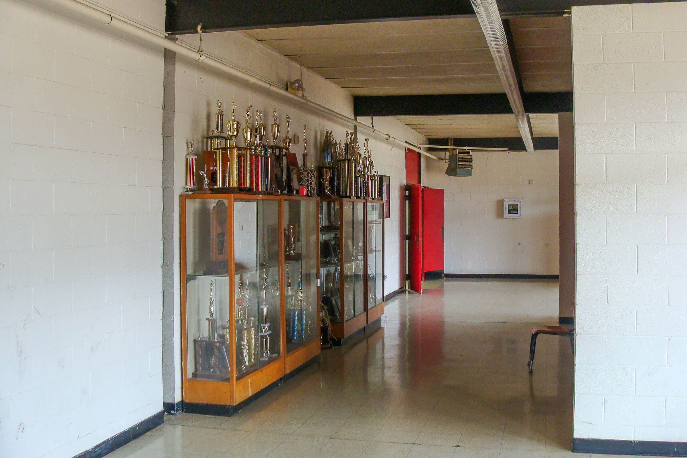 Corridor showing a trophy case, red door, polished floor and painted block walls