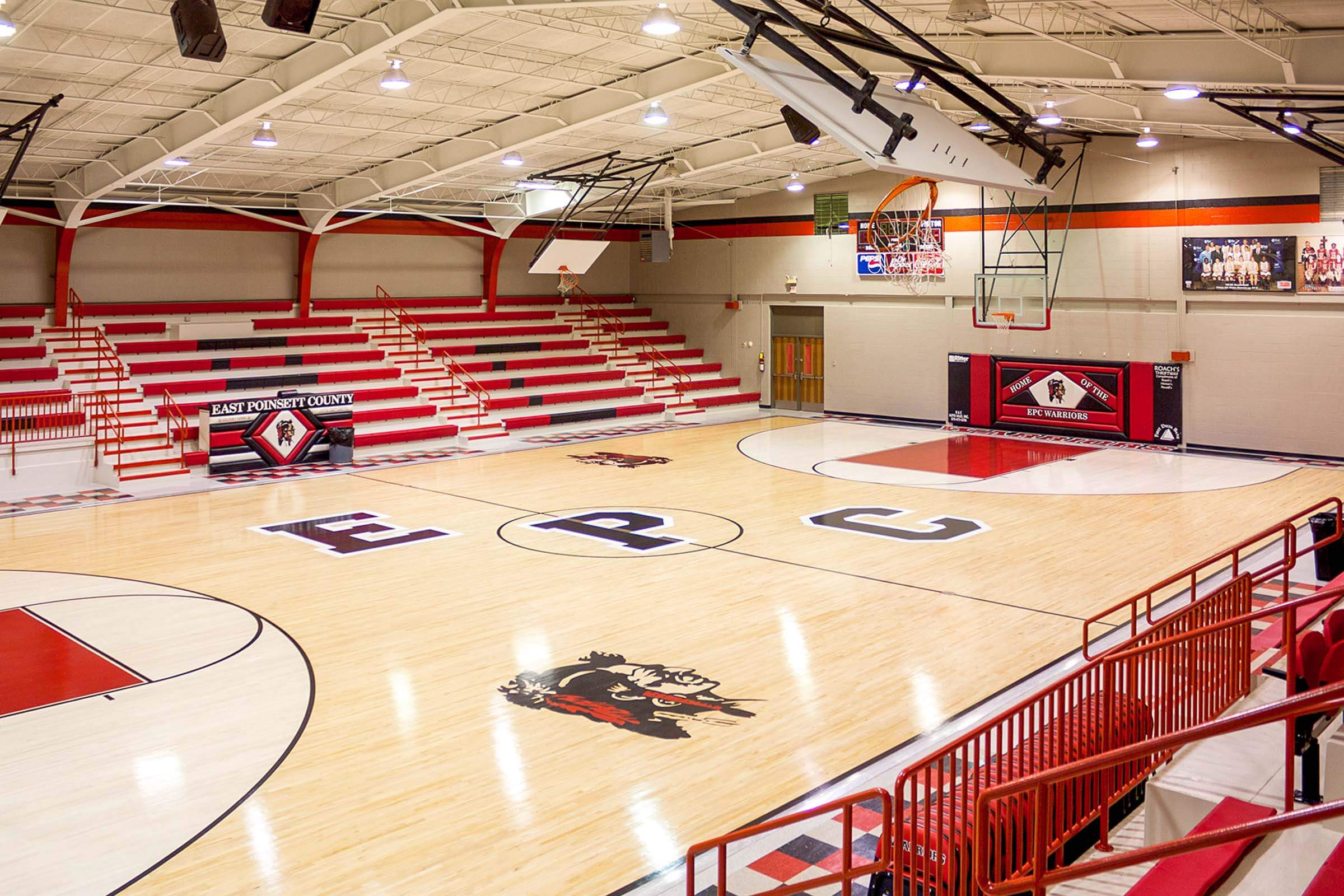 Another panoramic interior view of the renovated gym with court markings and red bleachers