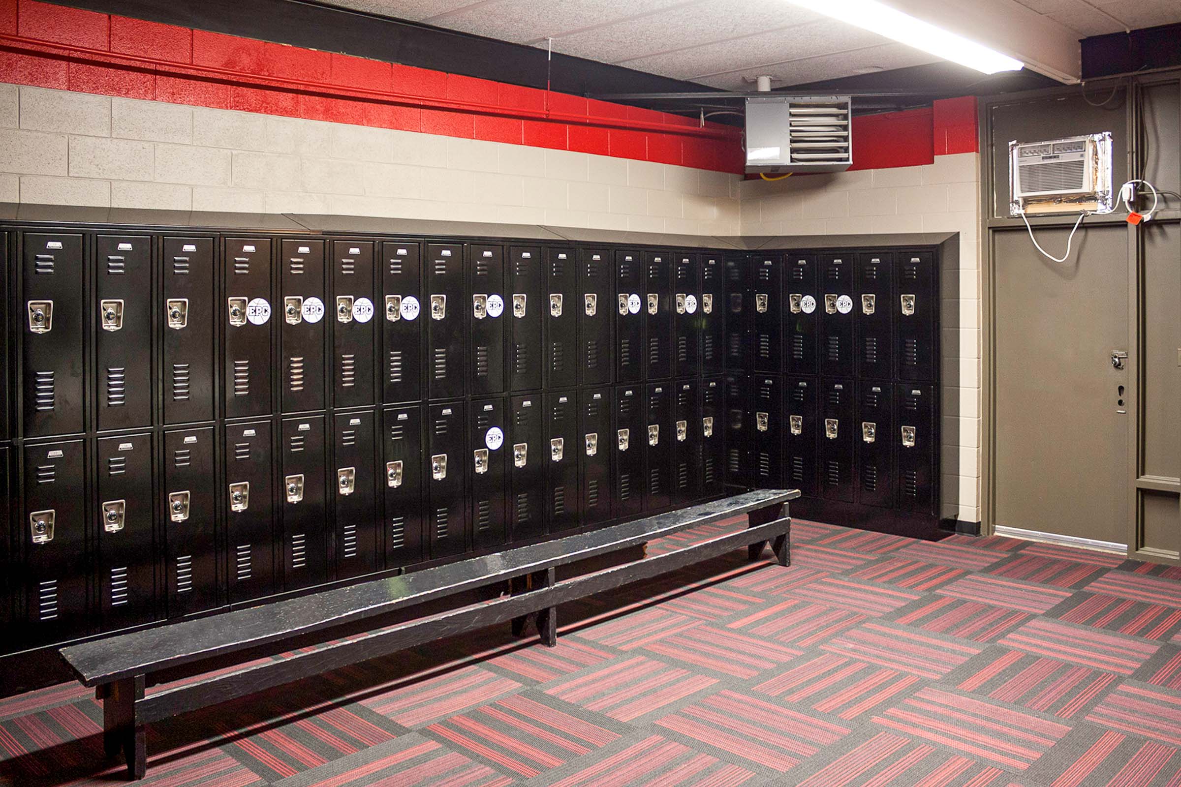 Locker room featuring black lockers, red-and-gray carpet and bench seating