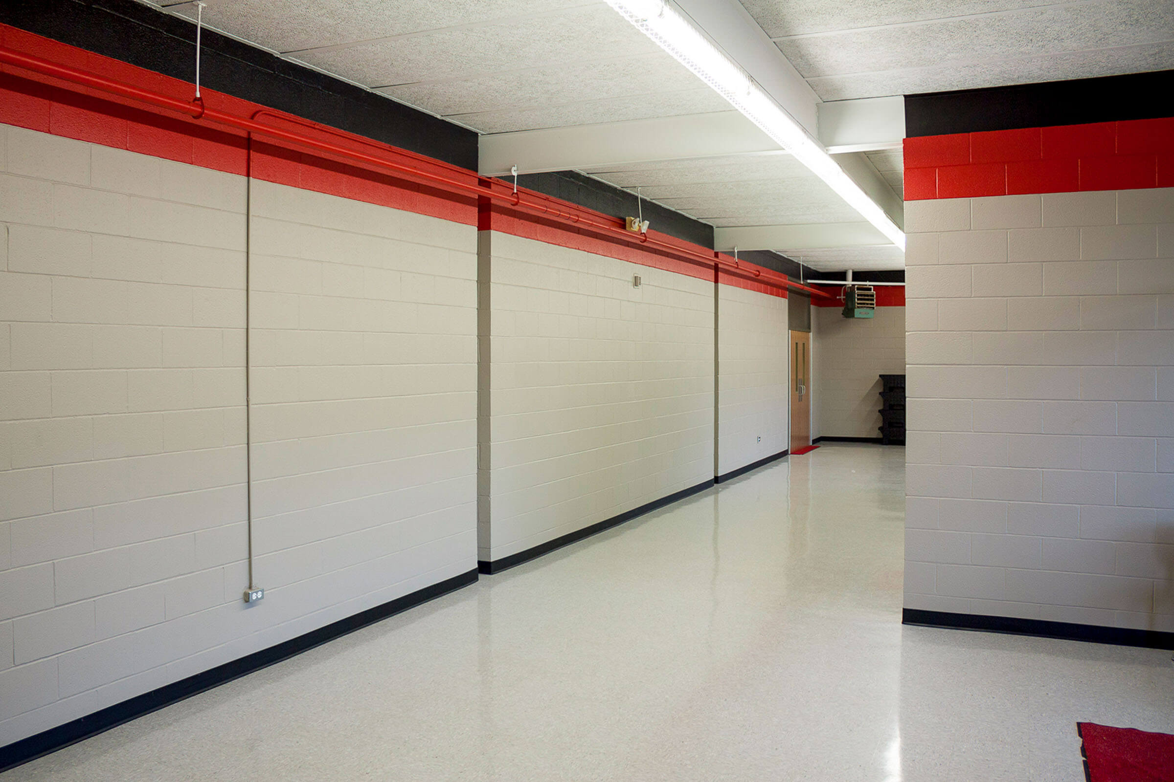 Renovated corridor with glossy floor and red-black accent band running along the wall