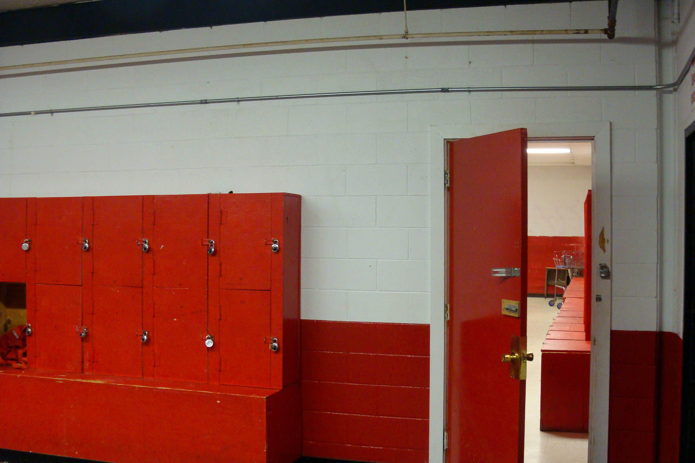 Corridor section featuring red lockers, red door and painted concrete walls