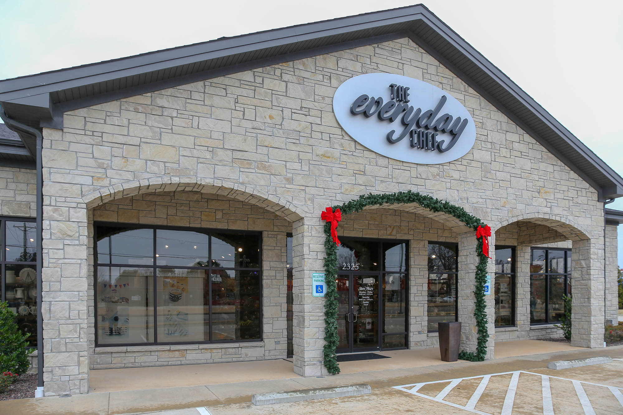 Close-up exterior shot of 'The Everyday Chef' storefront, highlighting the stone façade with arched entryways, large display windows