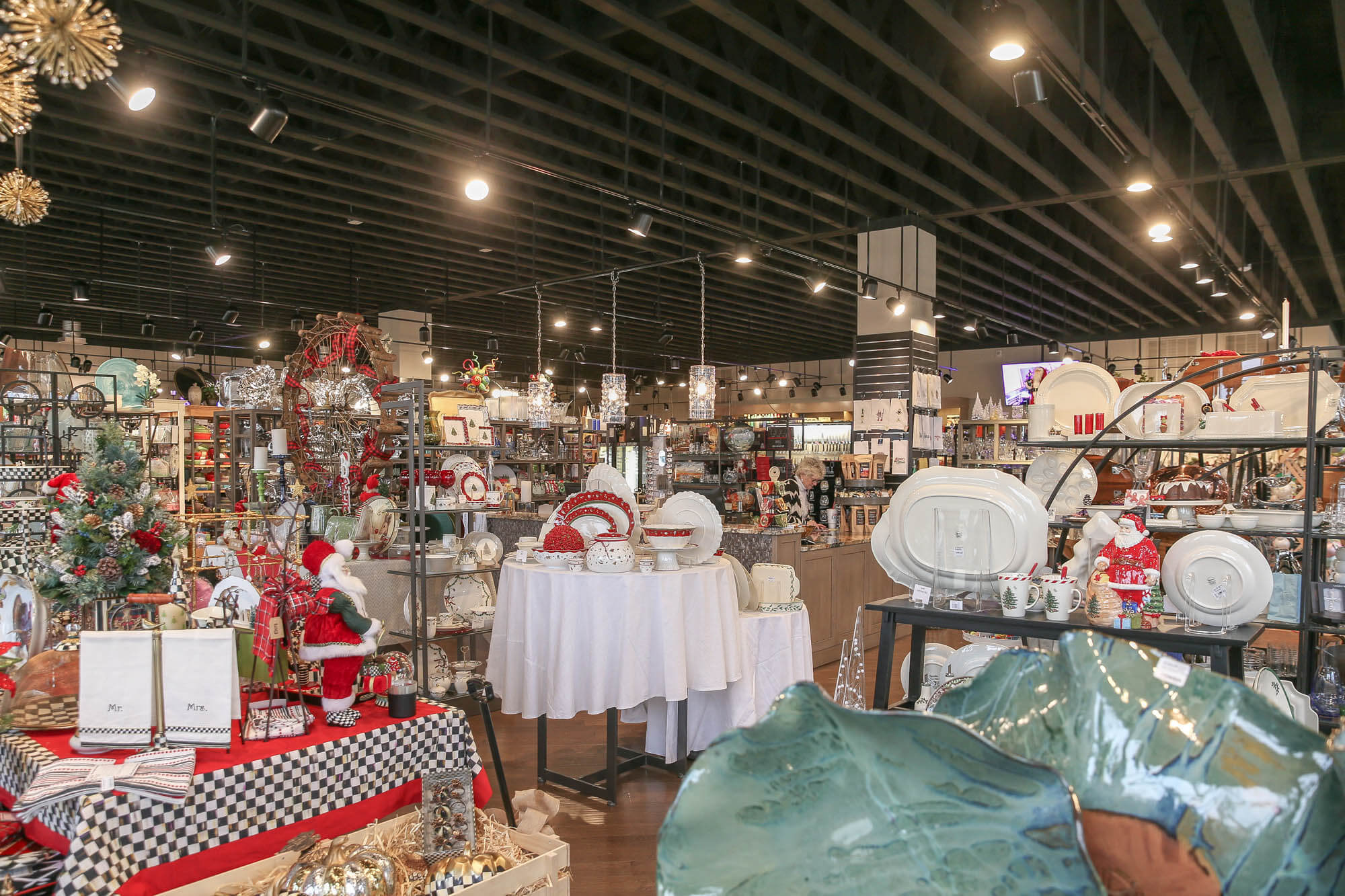 Interior shot - the open-concept design includes a high black ceiling with exposed beams, track lighting, and a central checkout counter in the background