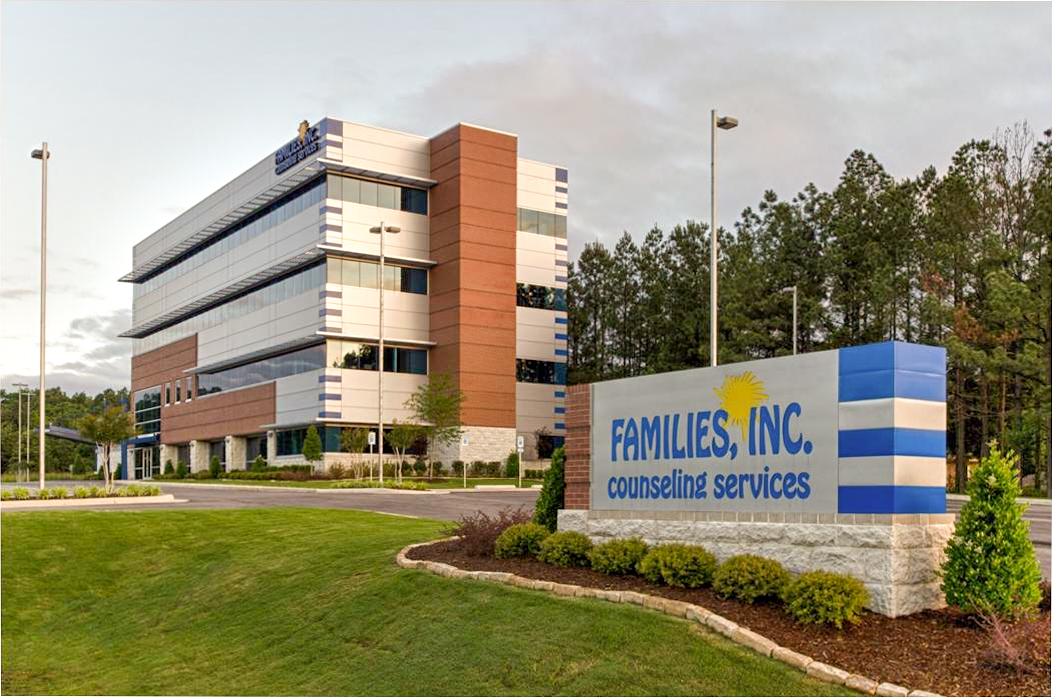 Exterior view of Families Inc. Counseling Services office facility, featuring a modern multi-story building with brick and glass facade, landscaped grounds, and prominent signage