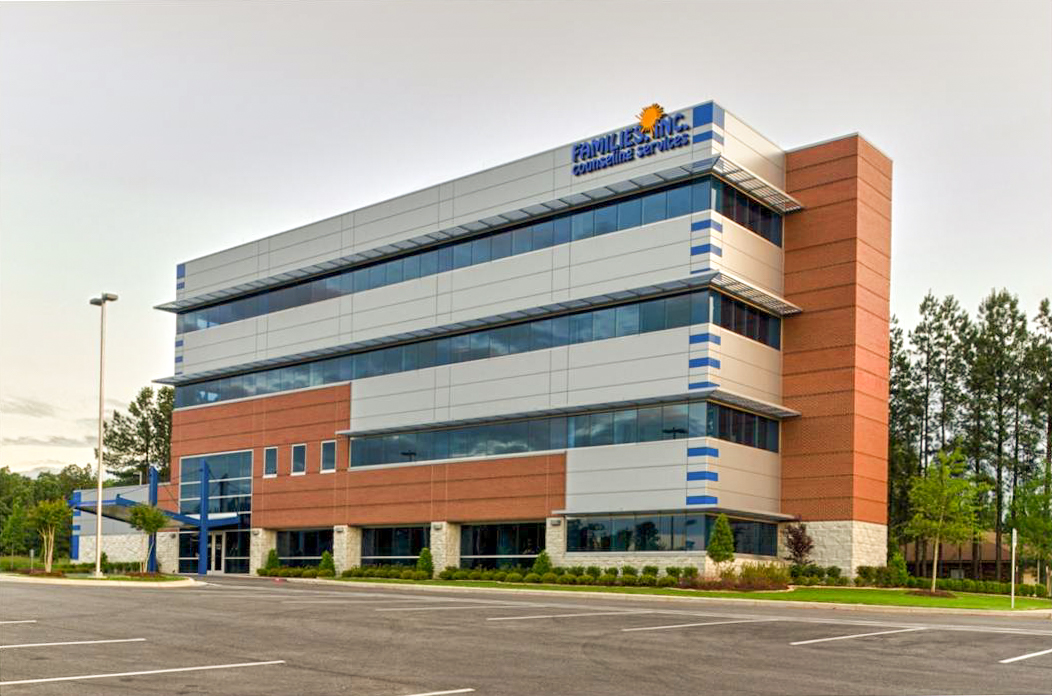 Families Inc. Counseling Services office building with modern architecture, featuring a mix of brick and metal paneling, expansive windows, and landscaped surroundings