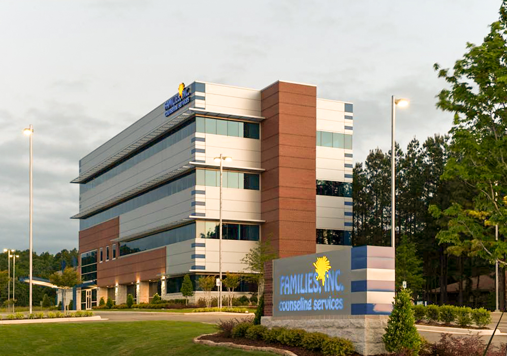 Families Inc. Counseling Services building at dusk, featuring modern brick and metal architecture, illuminated signage, and landscaped grounds