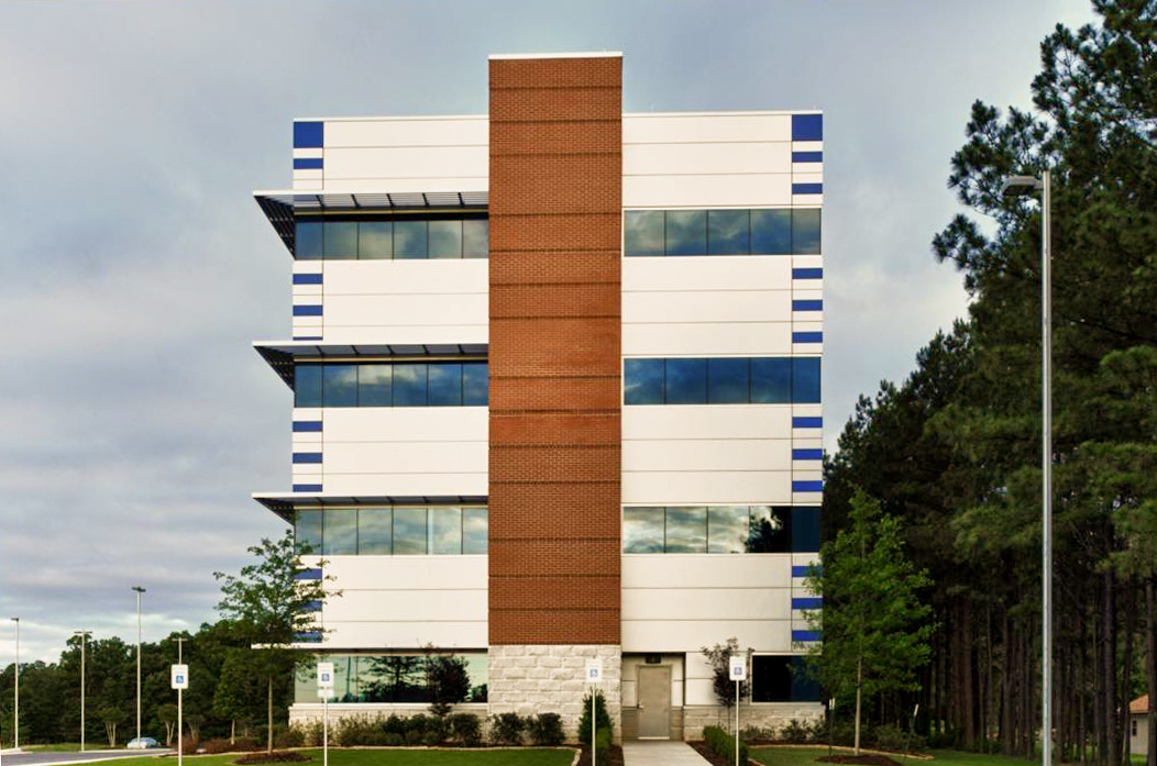 view of Families Inc. Counseling Services building showcasing modern design with brick and metal paneling, large reflective windows, and landscaped surroundings