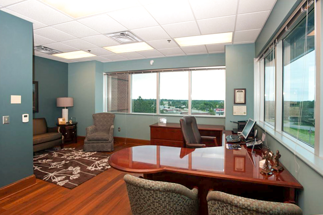 Executive office interior at Families Inc. with wood flooring, large desk, chairs, and window view of the city