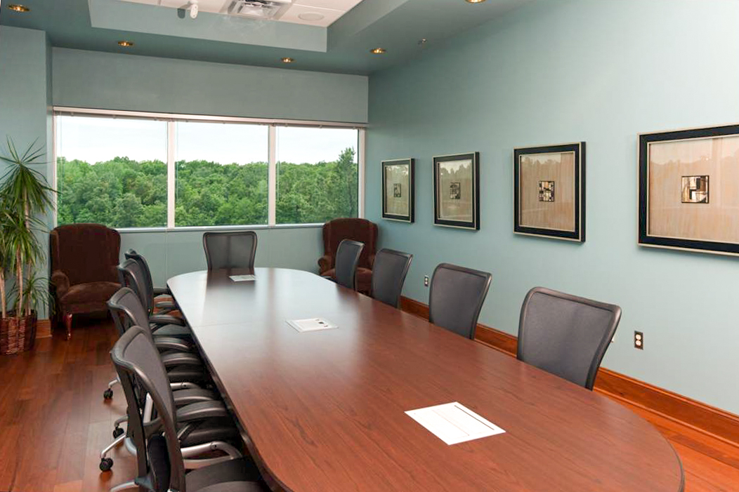 Families Inc. conference room with long wood table, office chairs, framed artwork, and large windows overlooking trees