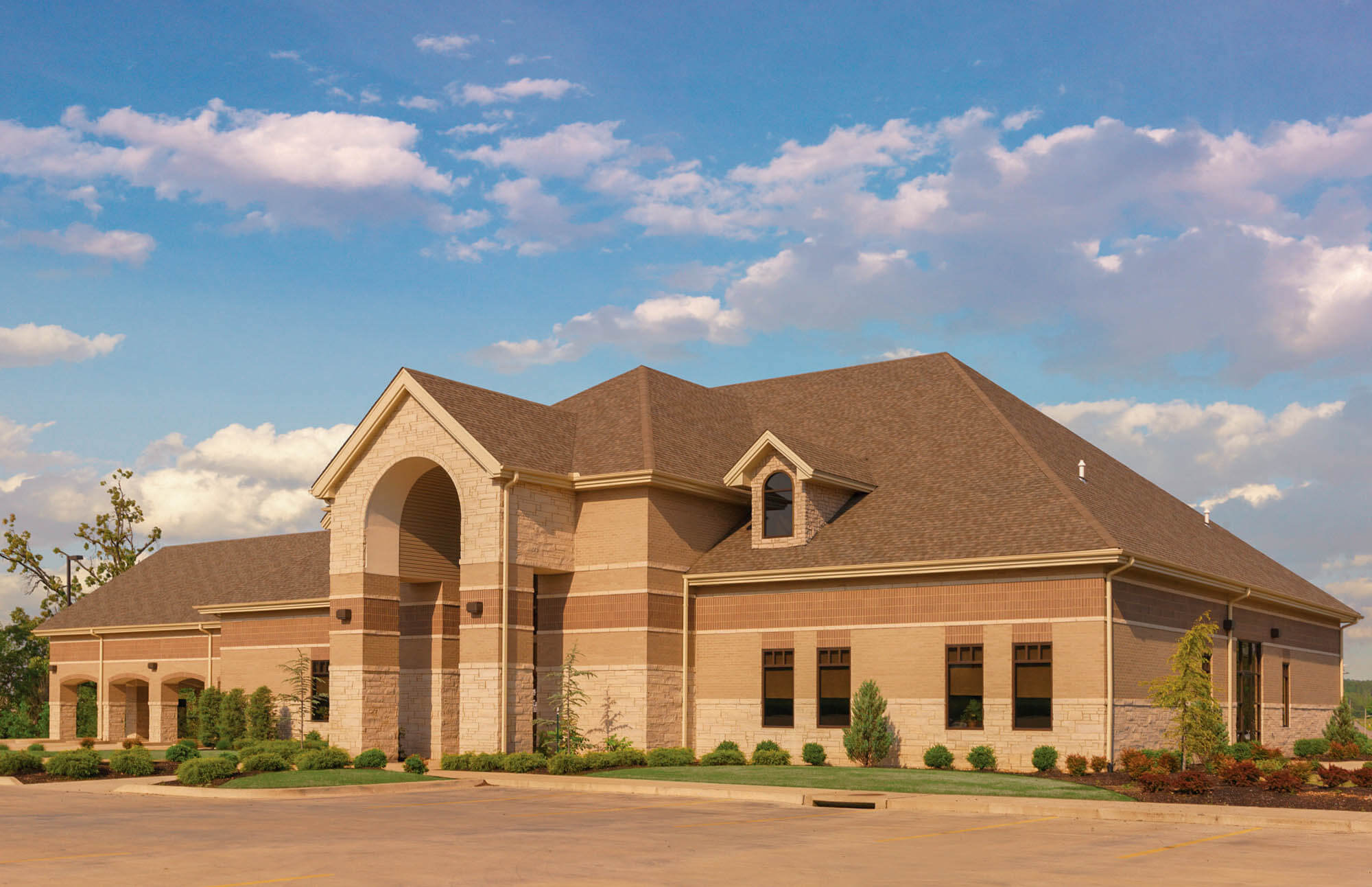 Exterior shot of Focus Bank in Paragould with decorative dormer windows, landscaped greenery, and a spacious parking area