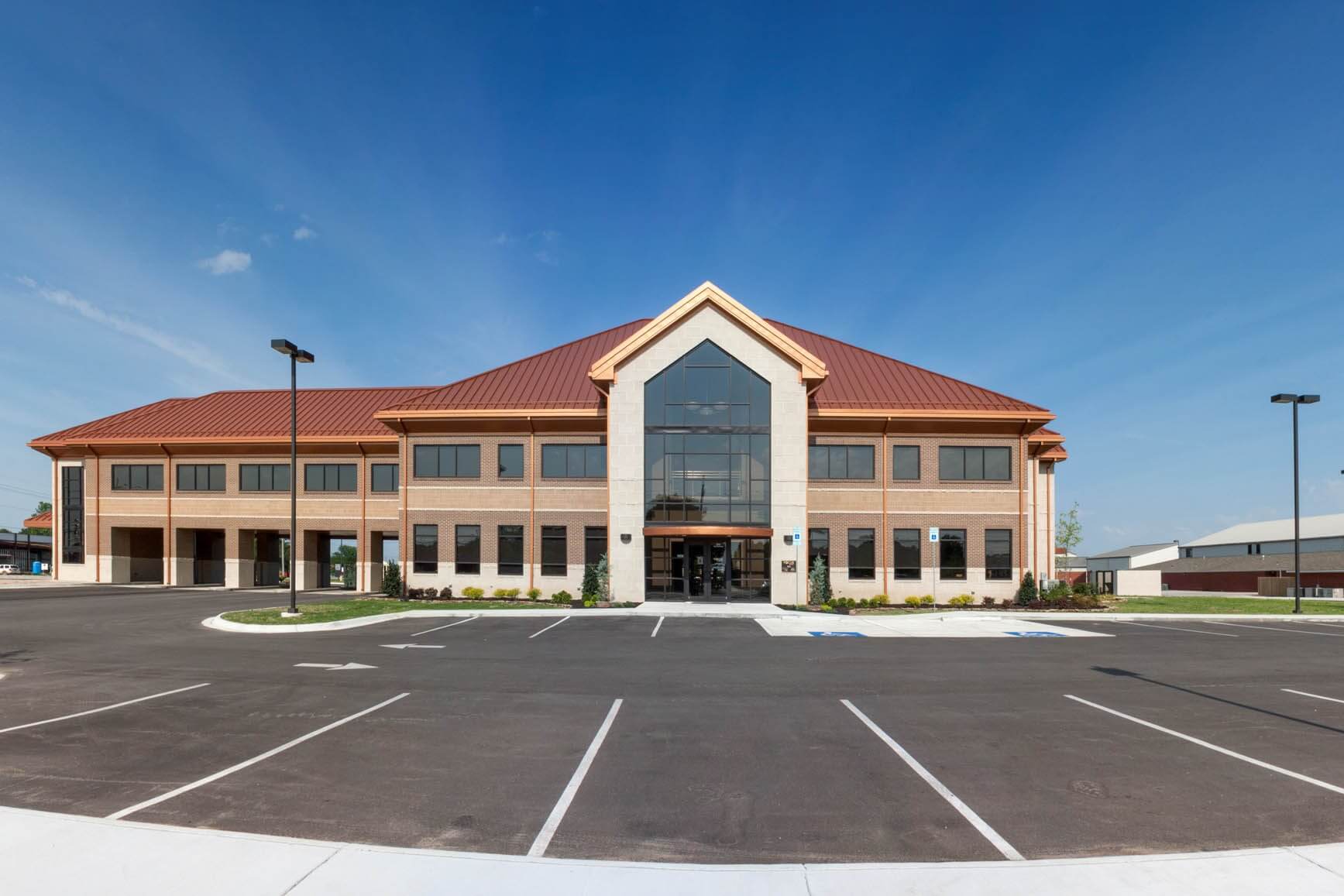 Exterior view of Focus Bank on Red Wolf Boulevard in Jonesboro, Arkansas, featuring a two-story brick and stone building with a steep red metal roof, central glass entryway, and surrounding parking lot