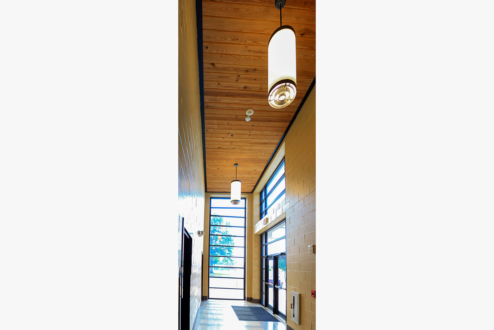 Entrance lobby featuring wood plank ceiling, pendant lights and tall windows captured from a vertical angle