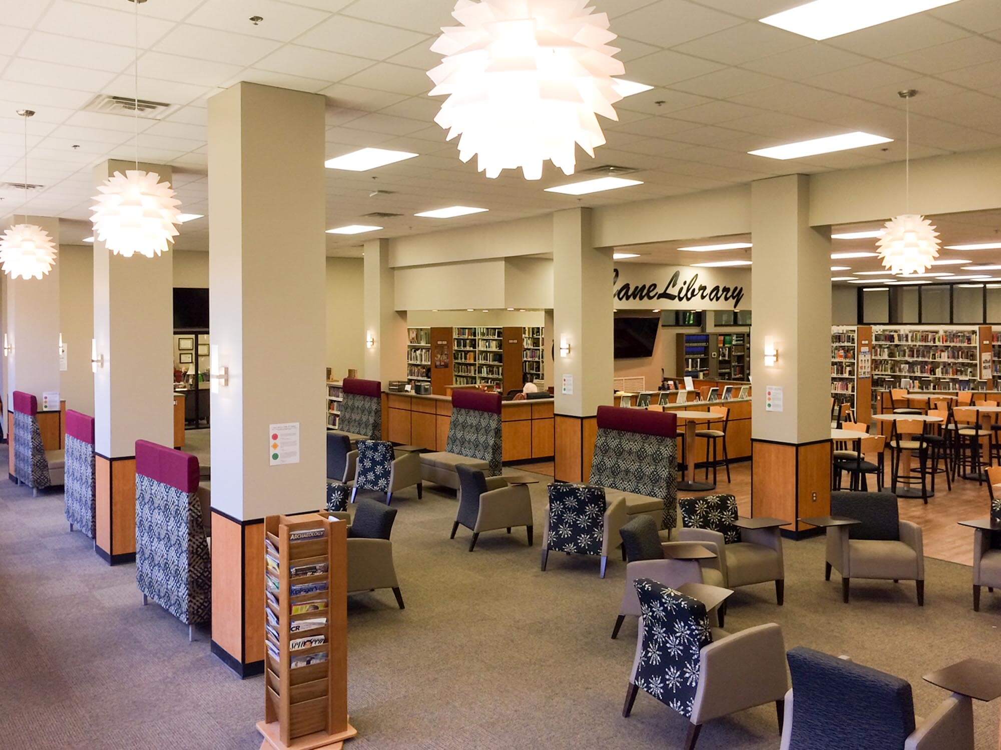 Modernized library seating area with lounge chairs, café tables, columns and starburst pendant lights