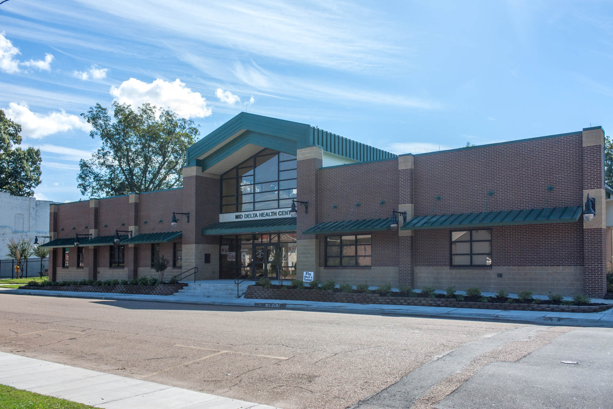 Long side view of the building highlighting brick façade and green awnings