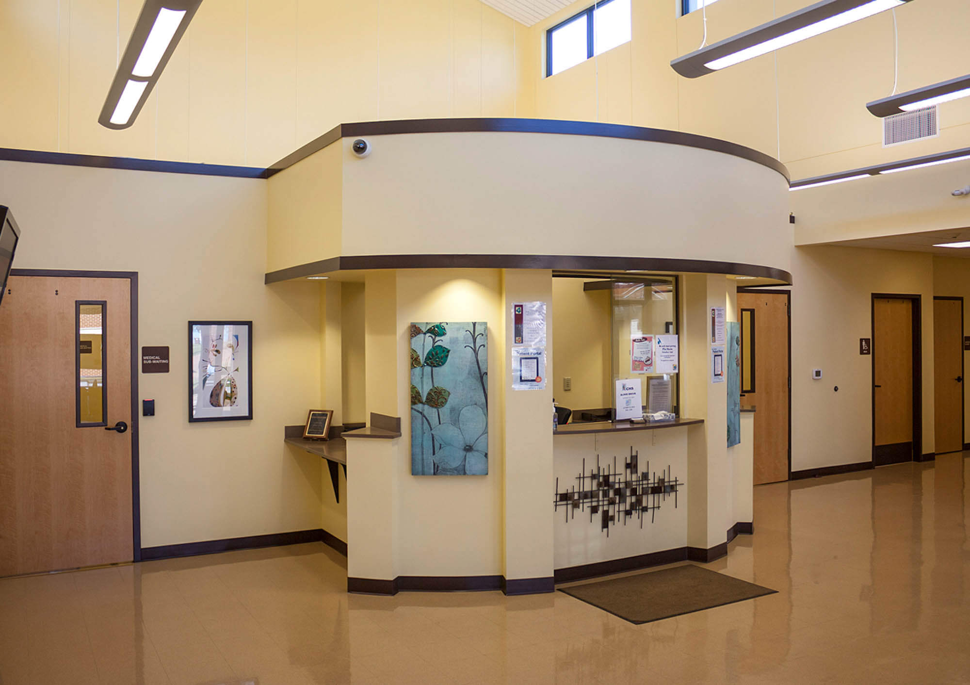 Interior reception area with curved reception desk under a high ceiling and beige walls