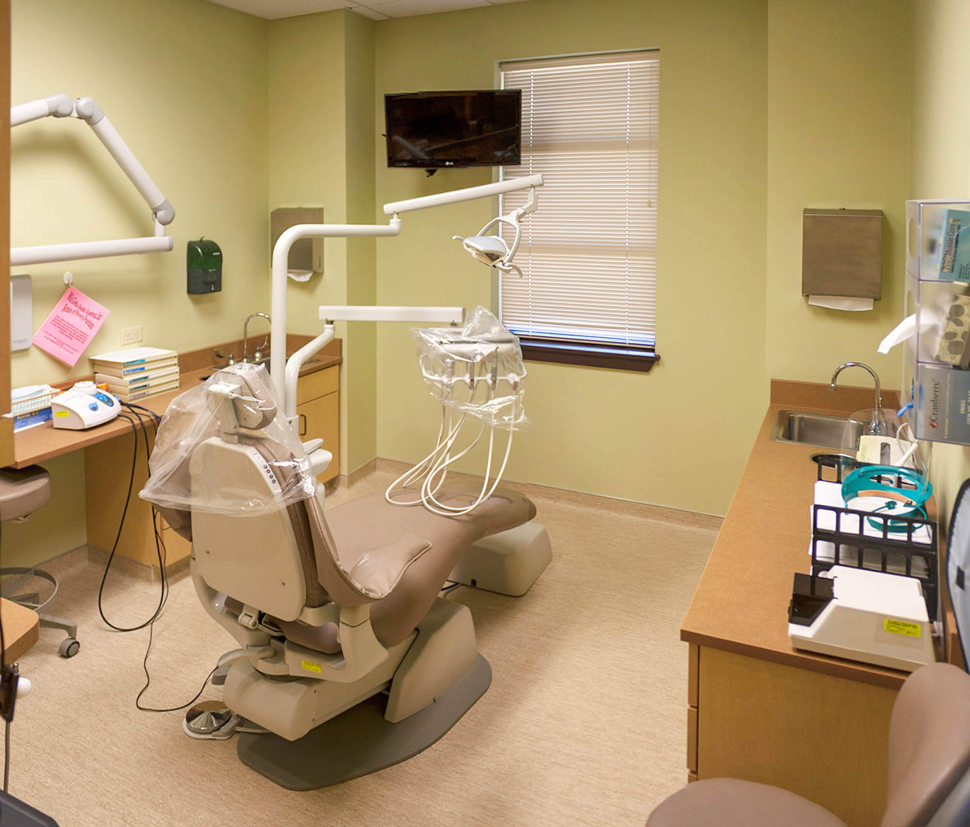 Dental exam room equipped with dental chair, overhead lights, sink and related equipment