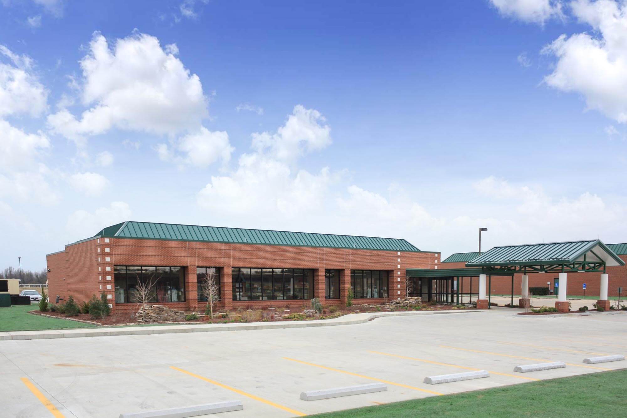 Long view of the clinic showing the covered drop‑off entrance and expansive parking area