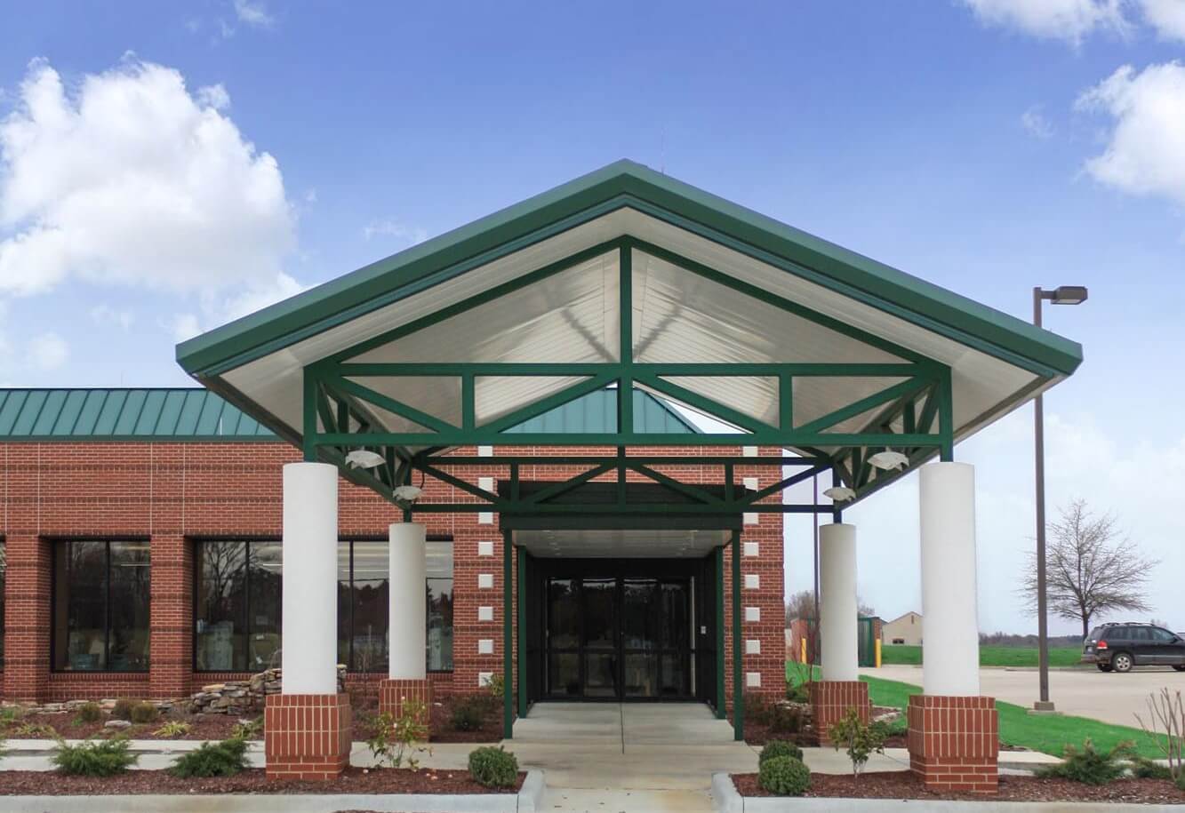 Close‑up of the green steel canopy supported by white columns at the main entrance