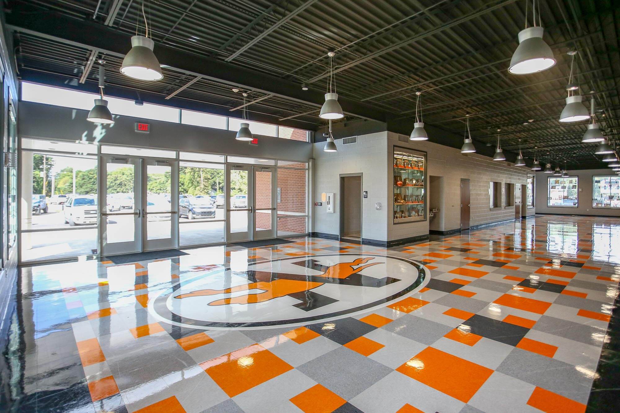 Lobby interior with glossy orange, gray and white checkerboard floor featuring a large greyhound logo, glass entrance doors and trophy case