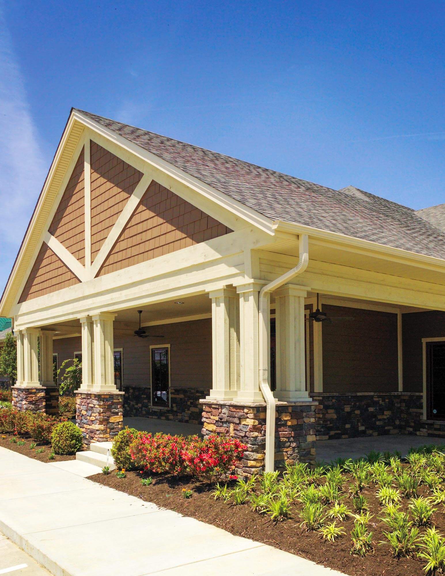 Angled view of Parkey-Davis Dental Clinic showing craftsman-style architecture with stone column bases, tan siding, and landscaped walkway