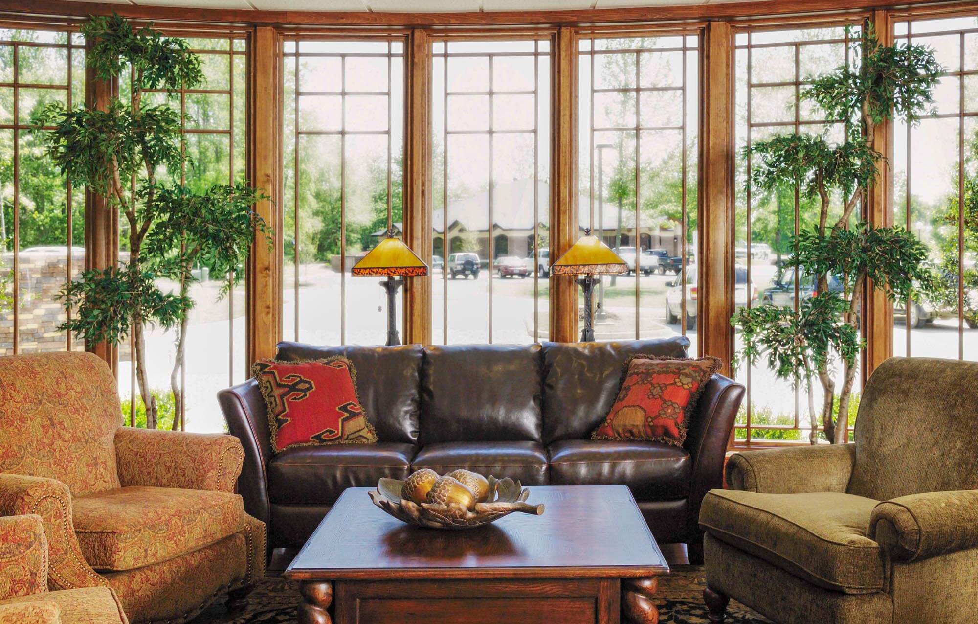 Cozy waiting area at Parkey-Davis Dental Clinic with large bay windows, leather sofa, upholstered chairs, decorative pillows, and warm natural lighting