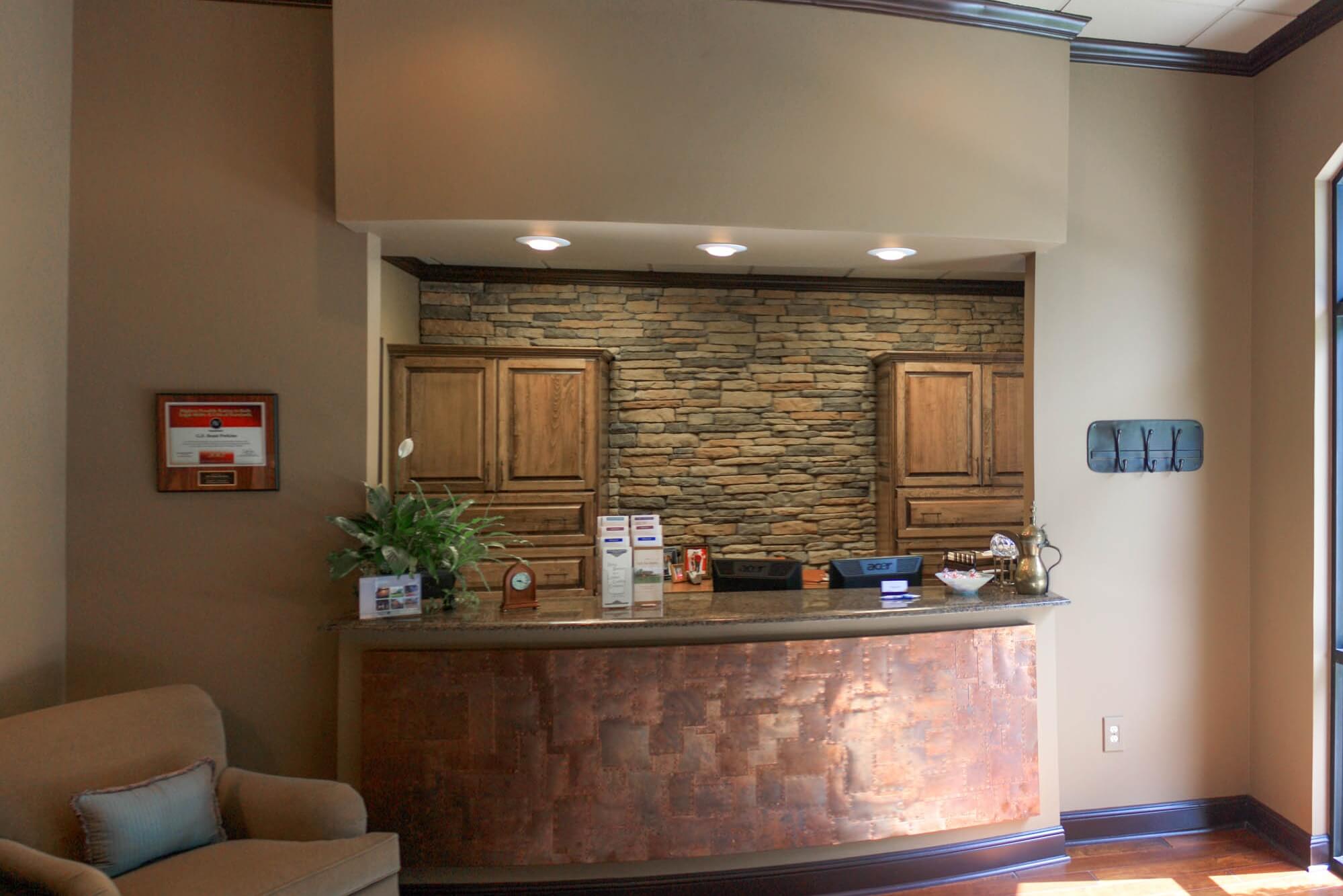 Close-up of the copper-panel reception counter with stacked-stone backdrop and seating visible to the side