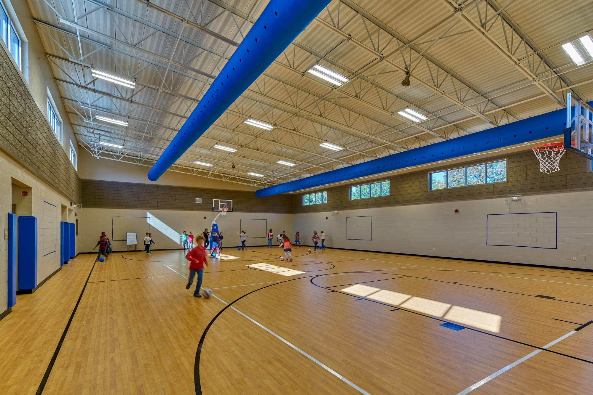 Students playing basketball in Richland Elementary gym with wood floor and blue ceiling ducts