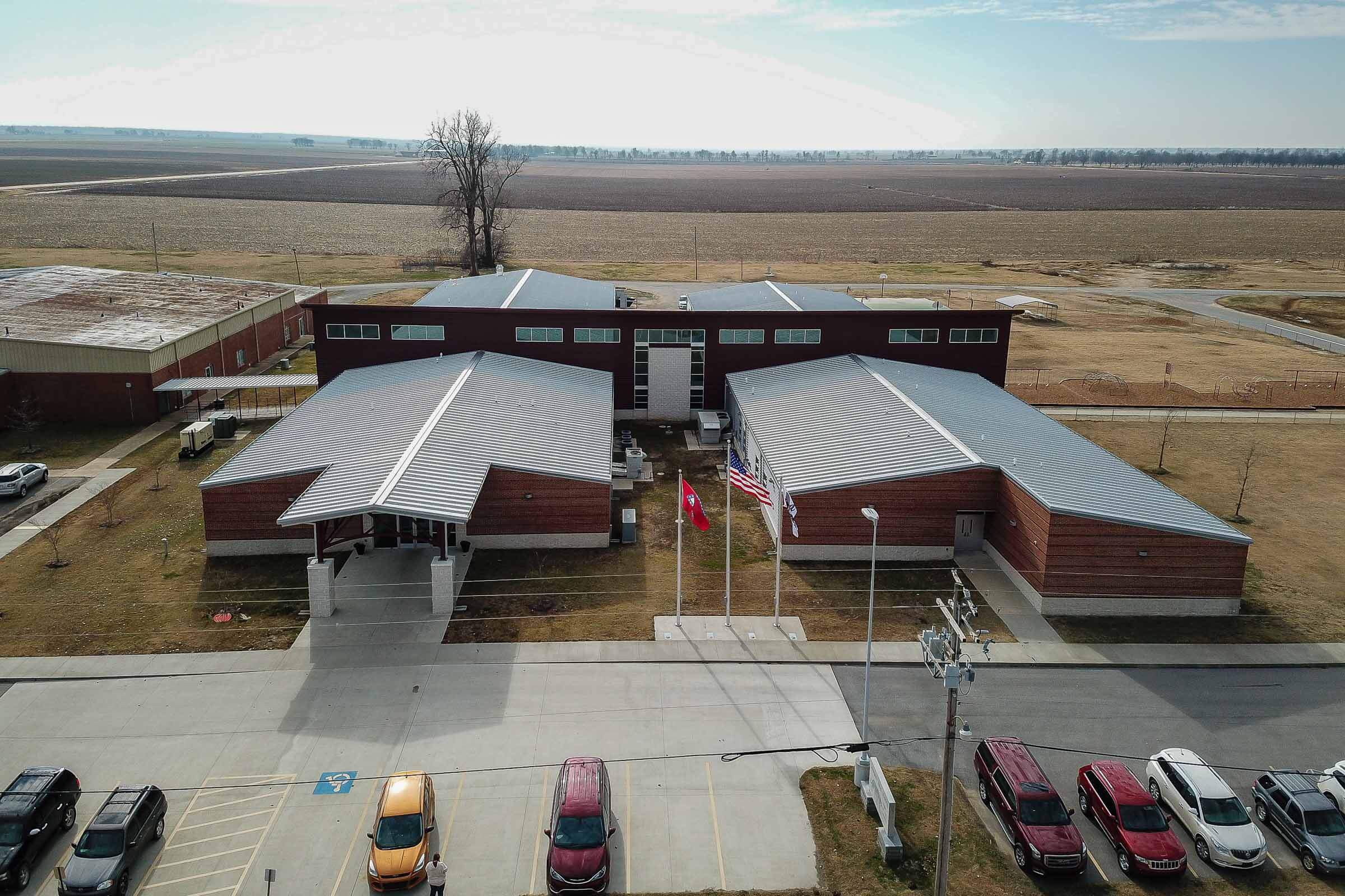 Aerial view of the campus showing multiple buildings connected by covered walkways with farmland in the background