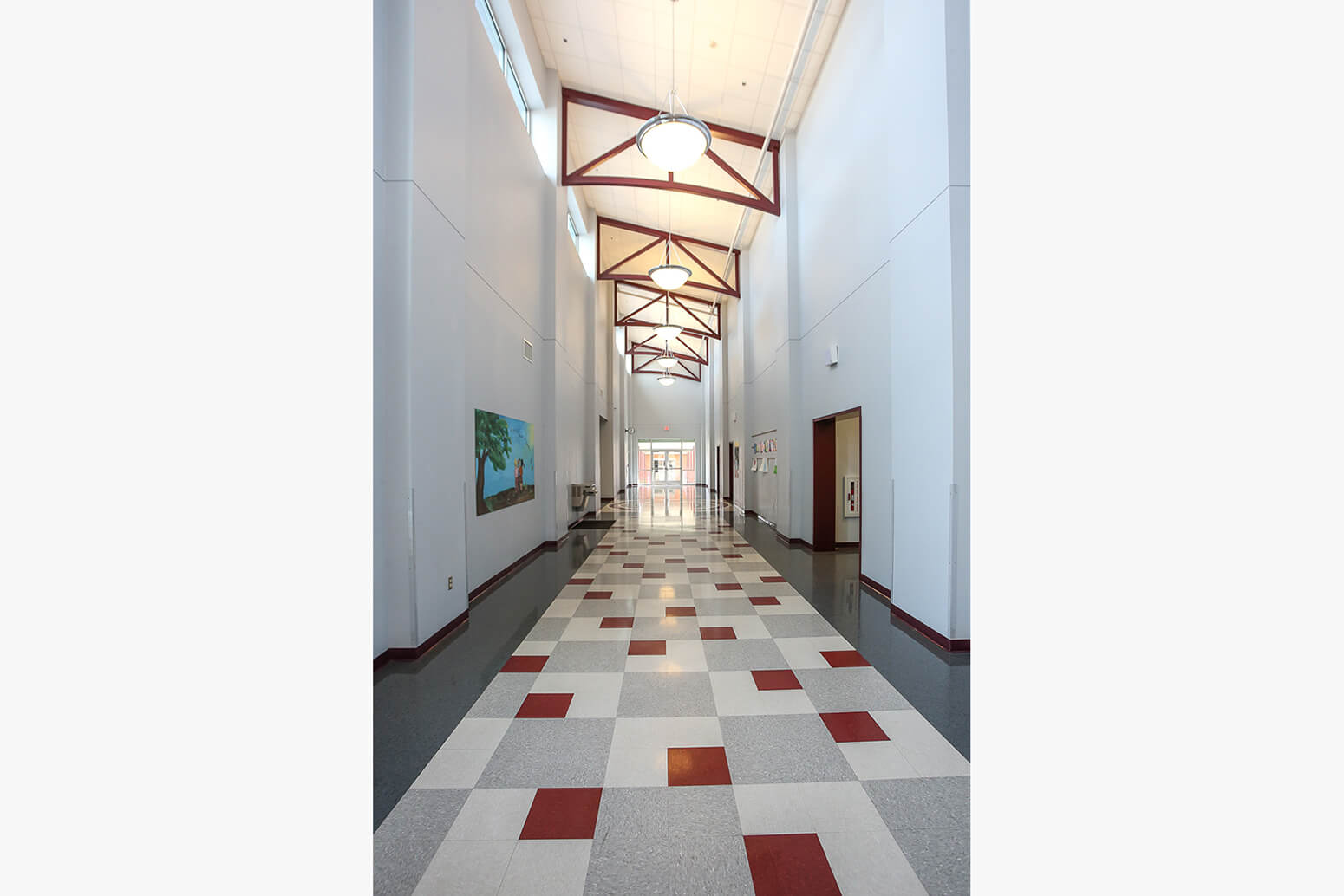 Tall atrium corridor with red structural trusses and patterned floor