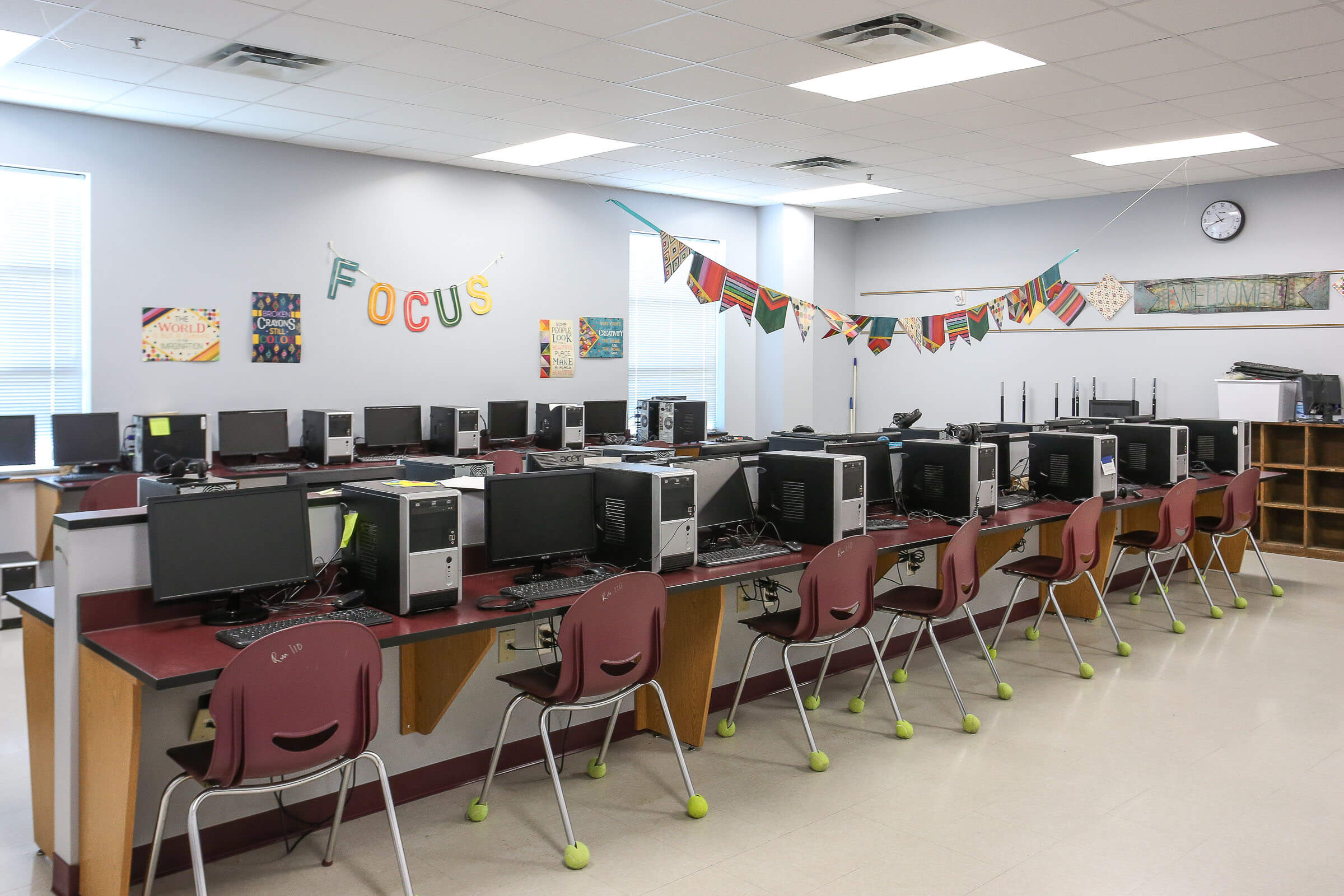 Computer lab featuring rows of desktop computers, maroon chairs, 'FOCUS' sign and decorative bunting