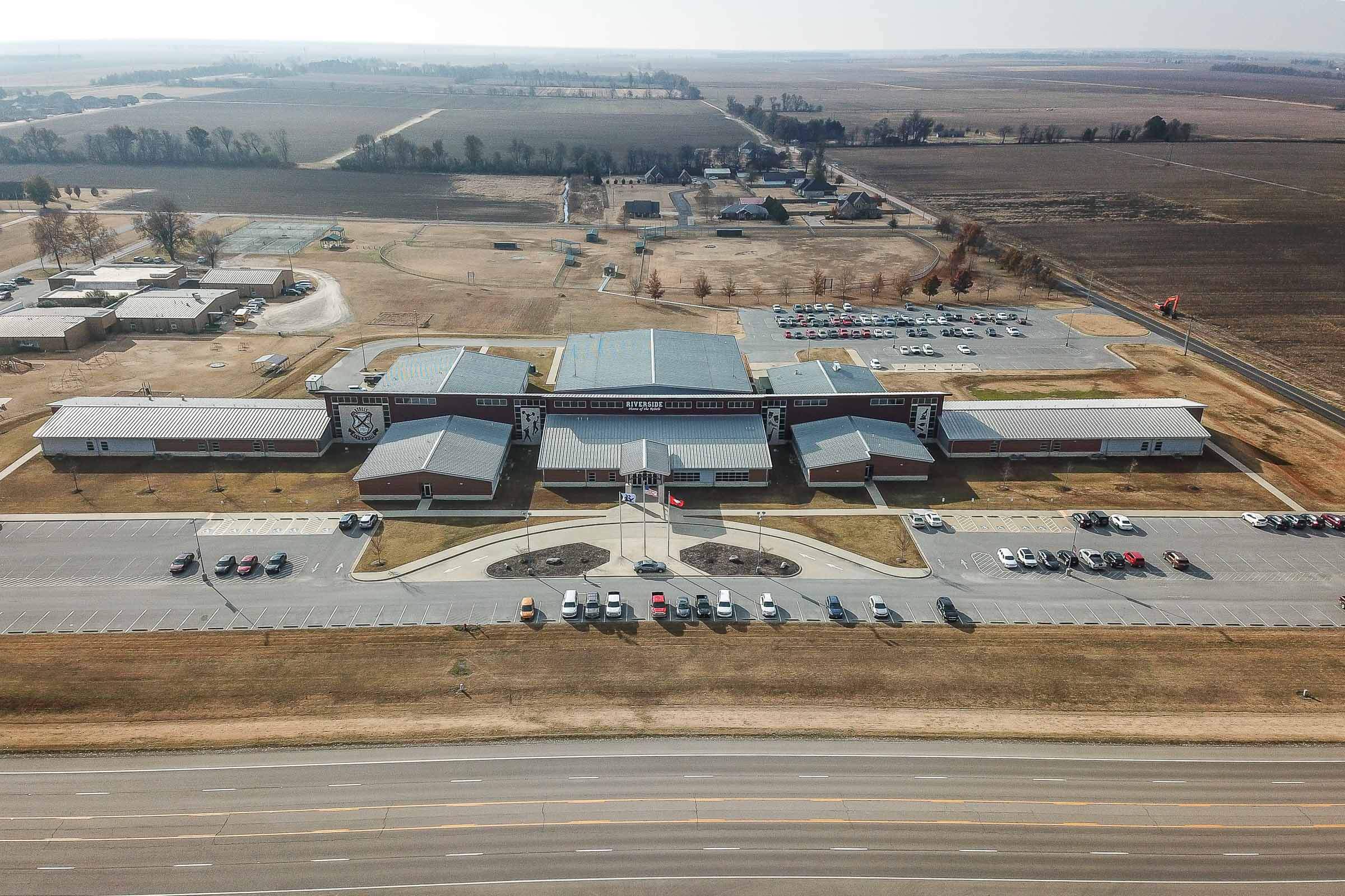 Aerial view of the Riverside High School complex with symmetrical wings and large parking lots in a rural setting