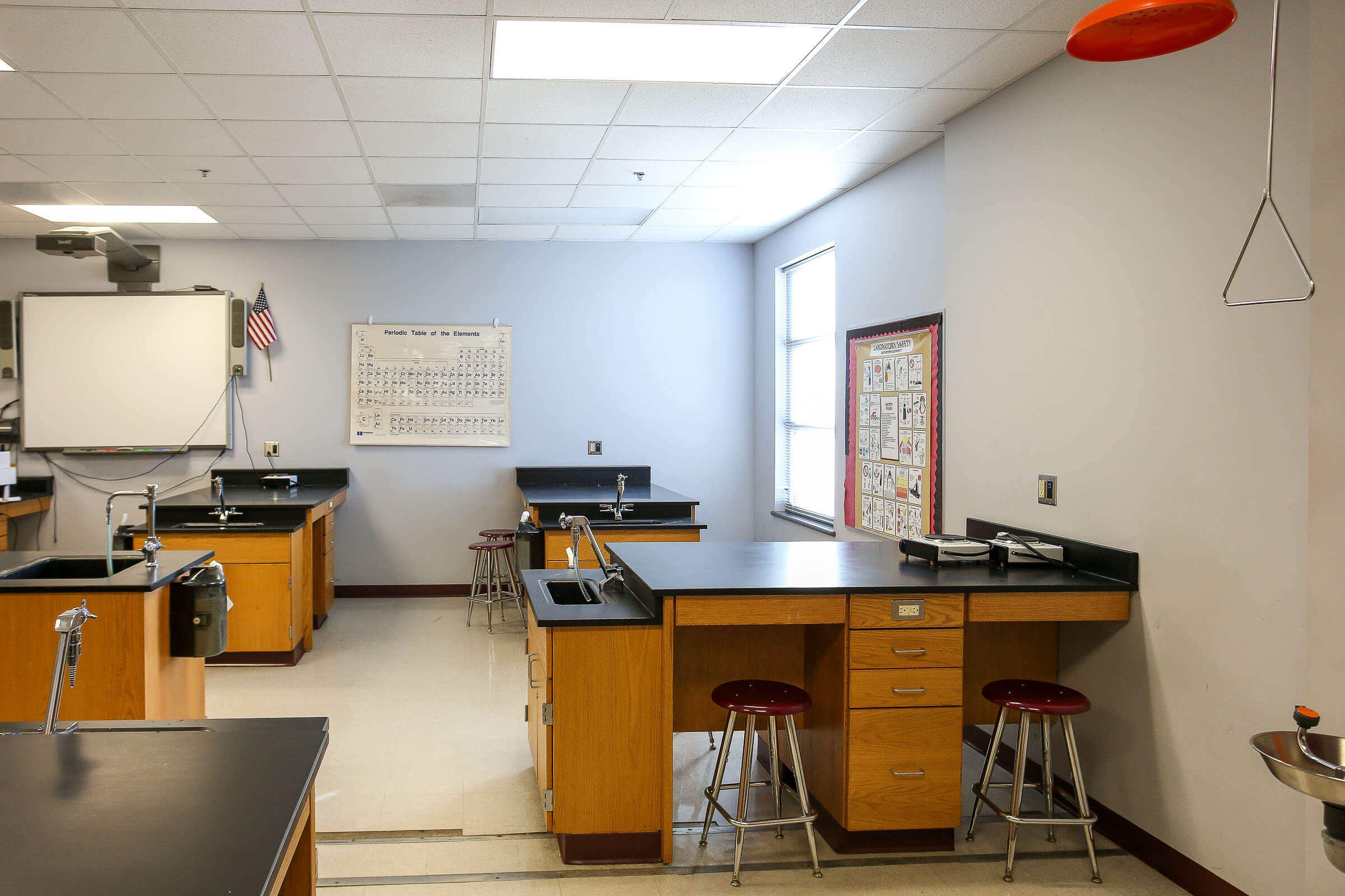 Science laboratory equipped with lab benches, sinks, periodic table poster and stools