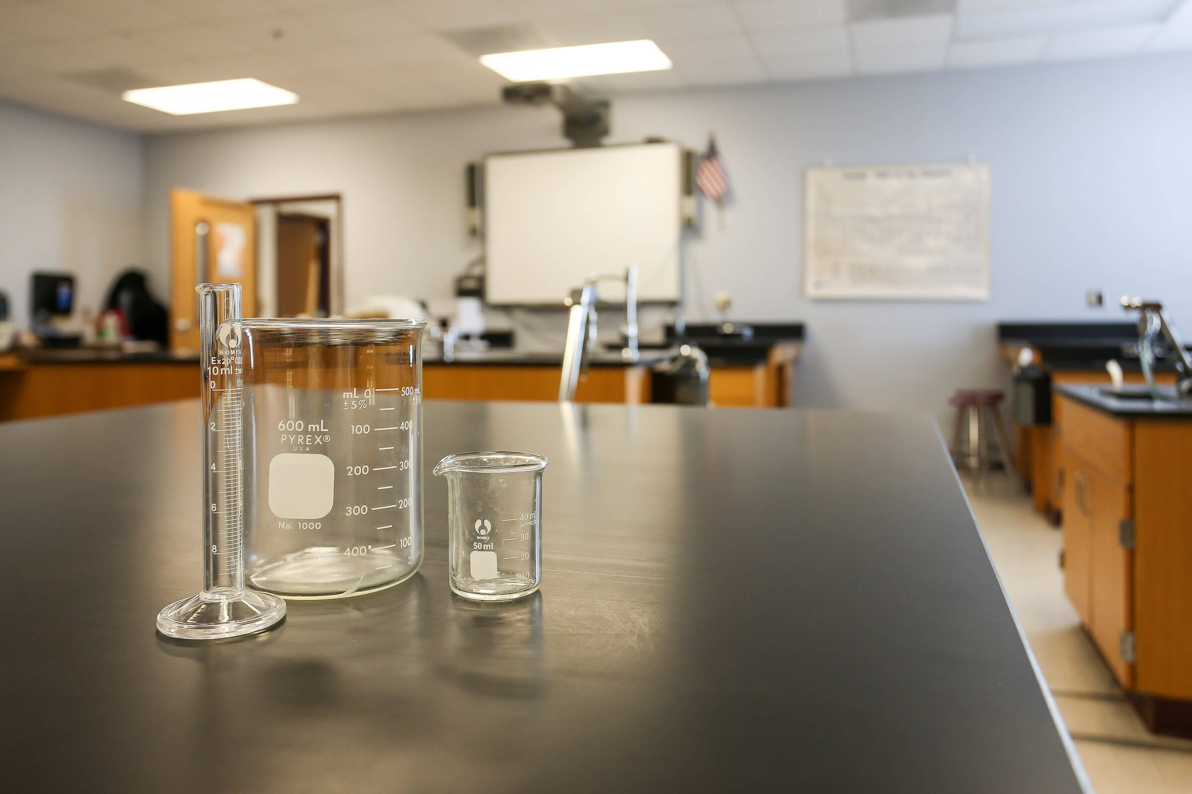Close-up of glassware on a laboratory countertop with blurred classroom background
