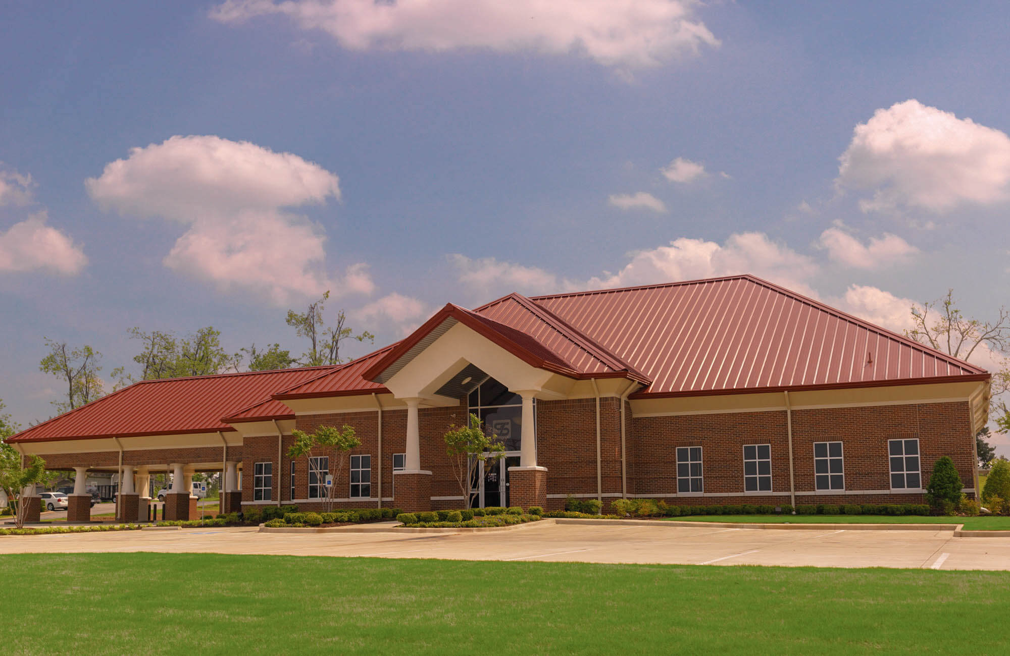 Oblique front-left view showing the bank building, covered drive lanes and manicured grass along the driveway