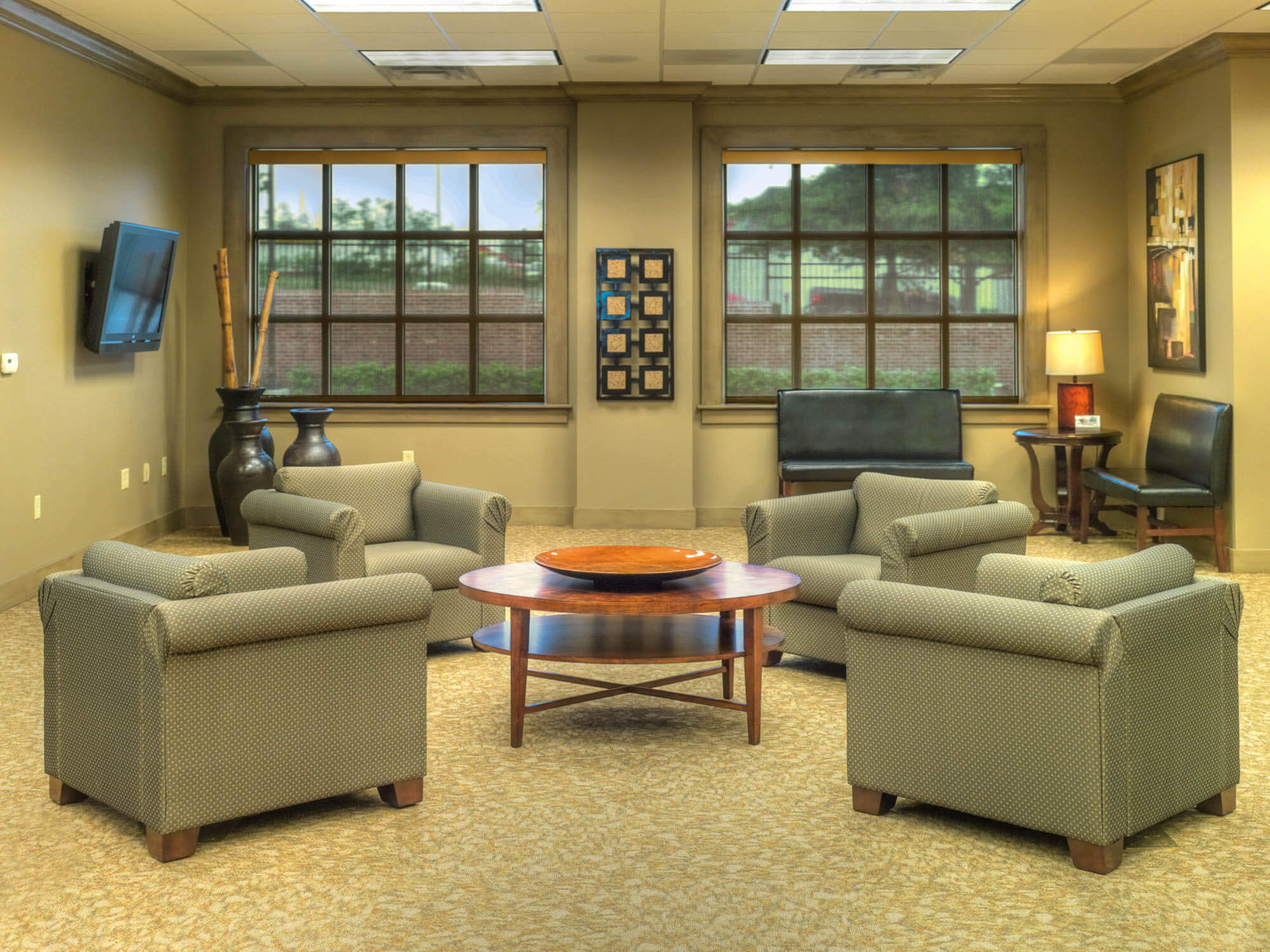 Lounge area with four upholstered chairs around a round table, large windows, side chairs and wall art