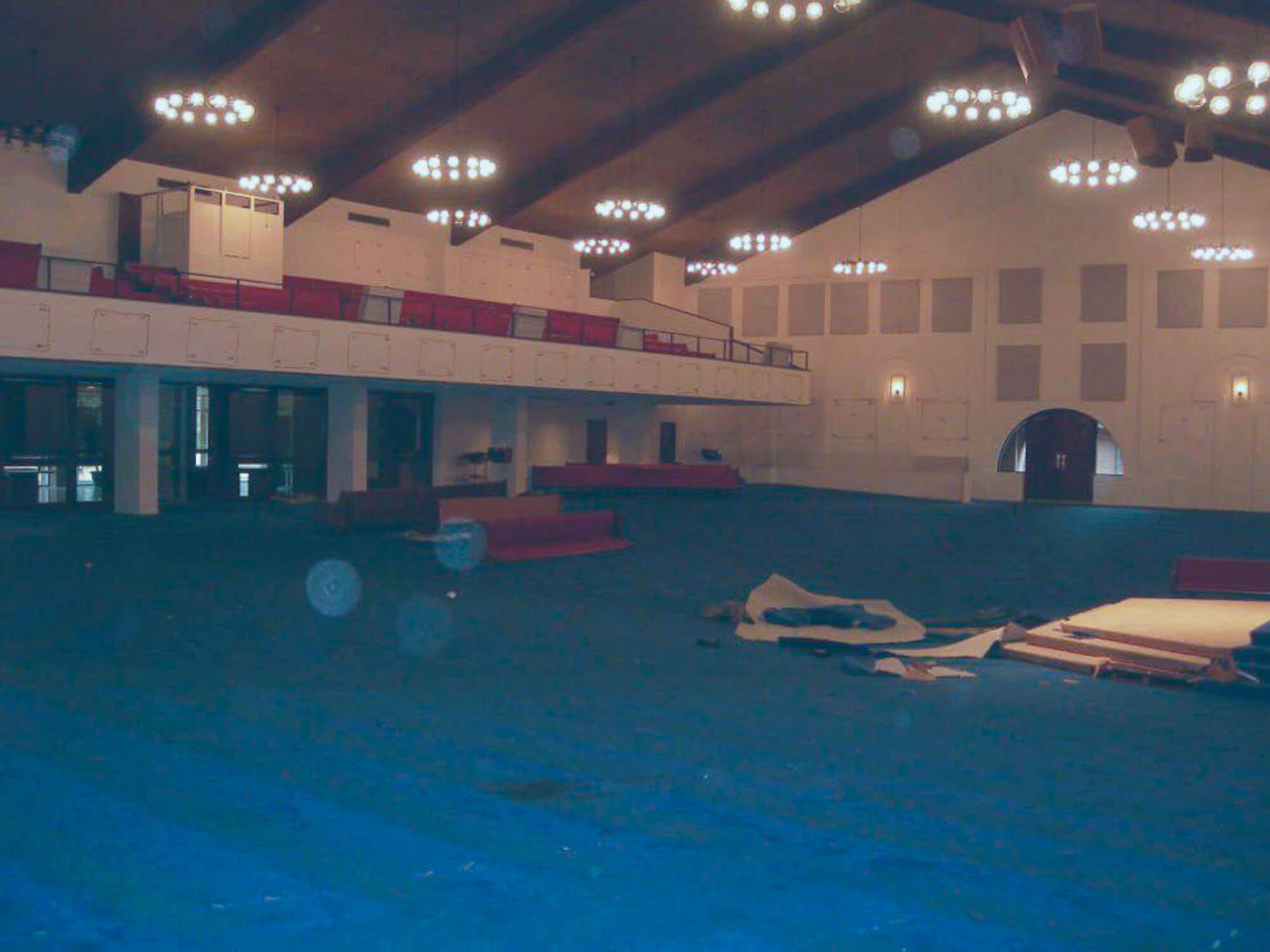 Southwest Church of Christ auditorium before renovation with blue carpet, red seating, and exposed balcony