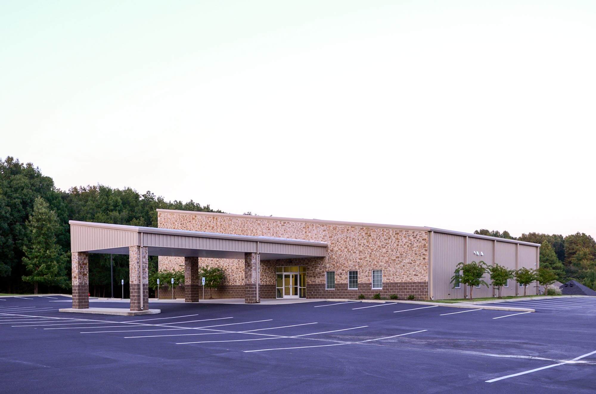 Exterior of Stoneridge Church of Christ with stone and metal facade, covered entry, and parking lot