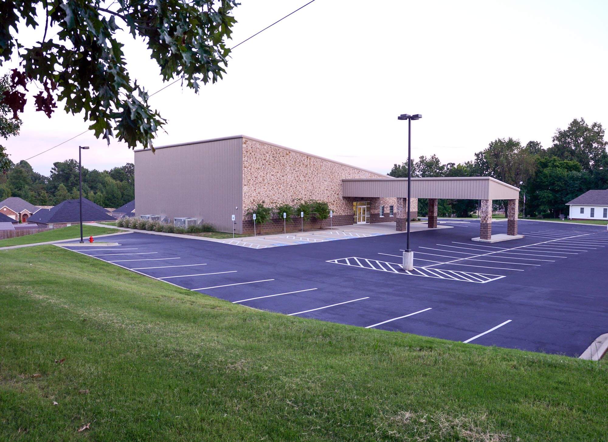 Angled view of Stoneridge Church of Christ with stone and metal exterior, covered entry, and parking lot