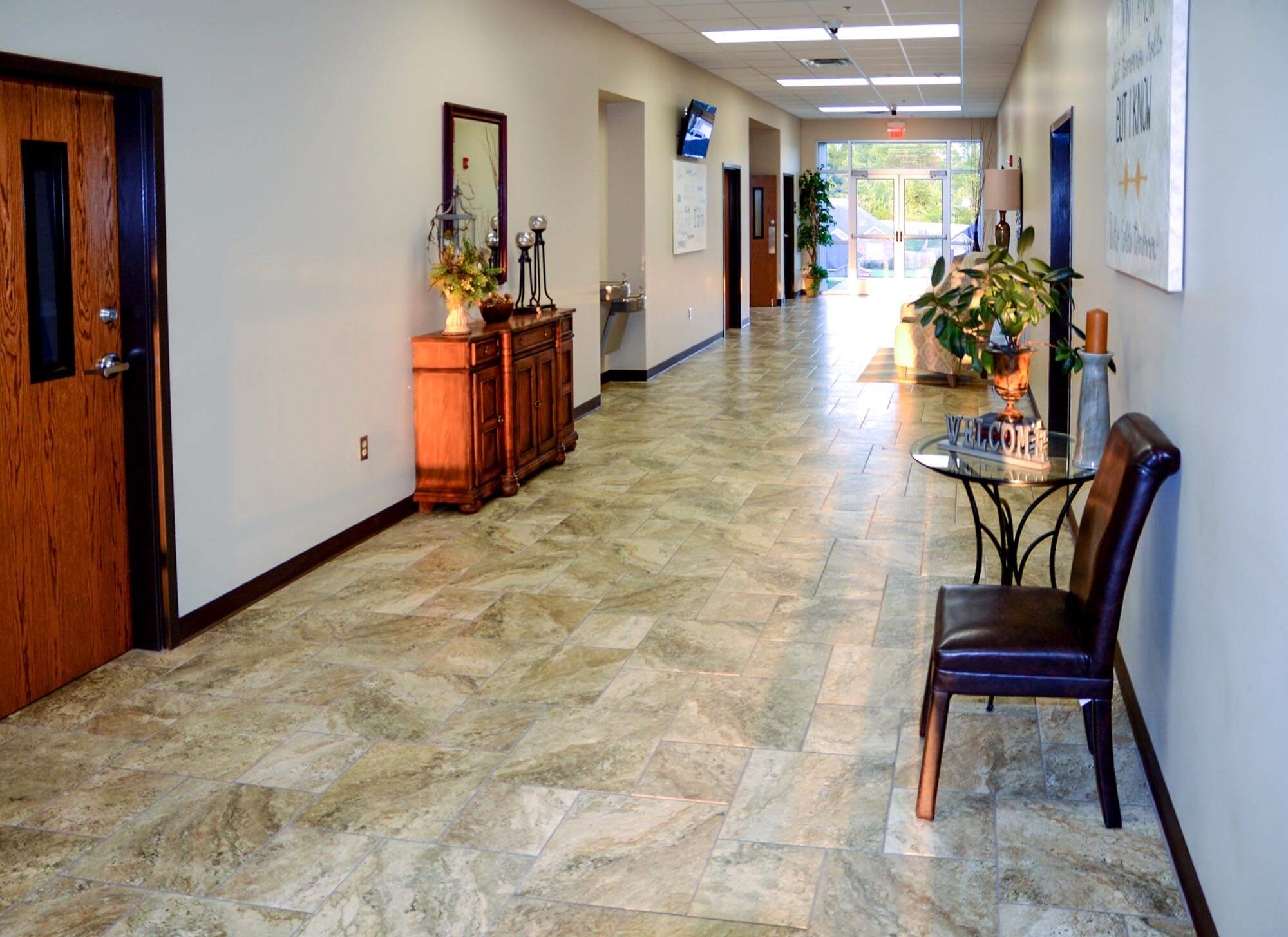 Lobby hallway of Stoneridge Church of Christ with tile flooring, welcome table, and wooden cabinet