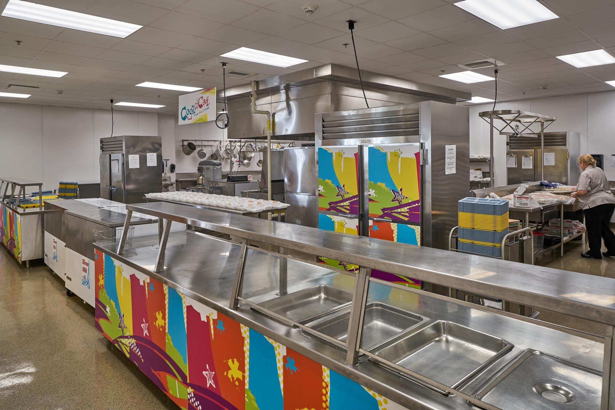 School cafeteria kitchen with serving line and colorful equipment panels