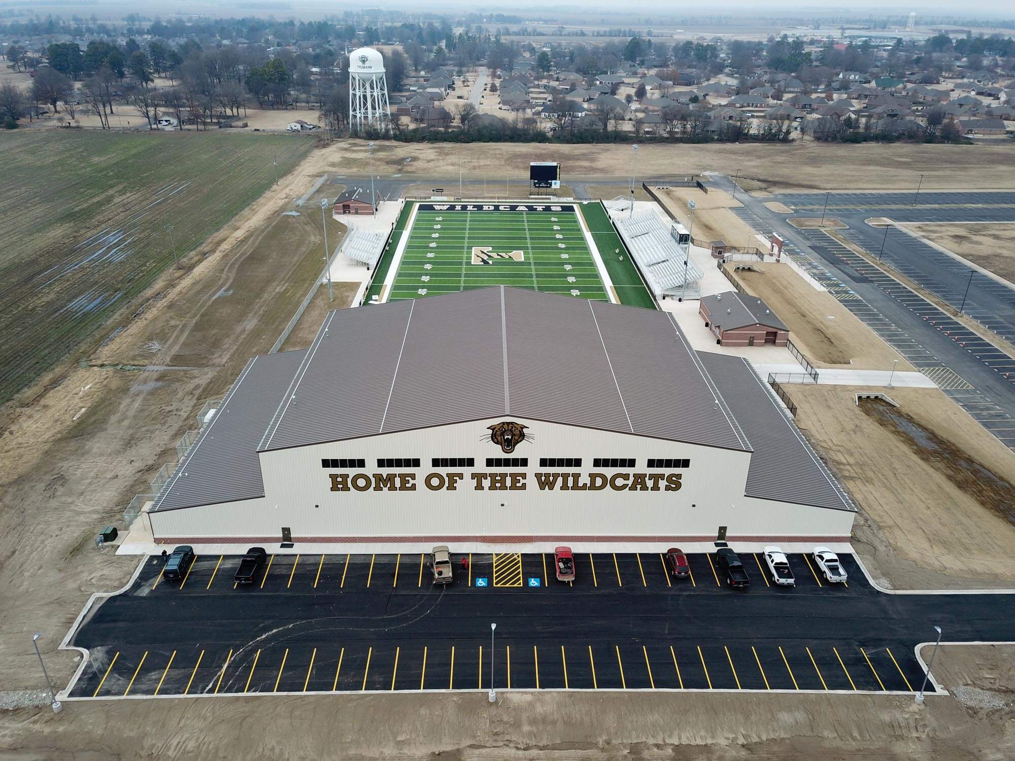 Aerial shot of the fieldhouse with large 'Home of the Wildcats' signage and turf stadium behind