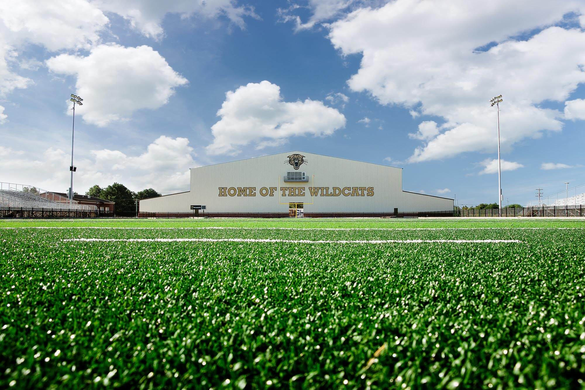 Low-angle ground view from the turf focusing on the fieldhouse and goalposts