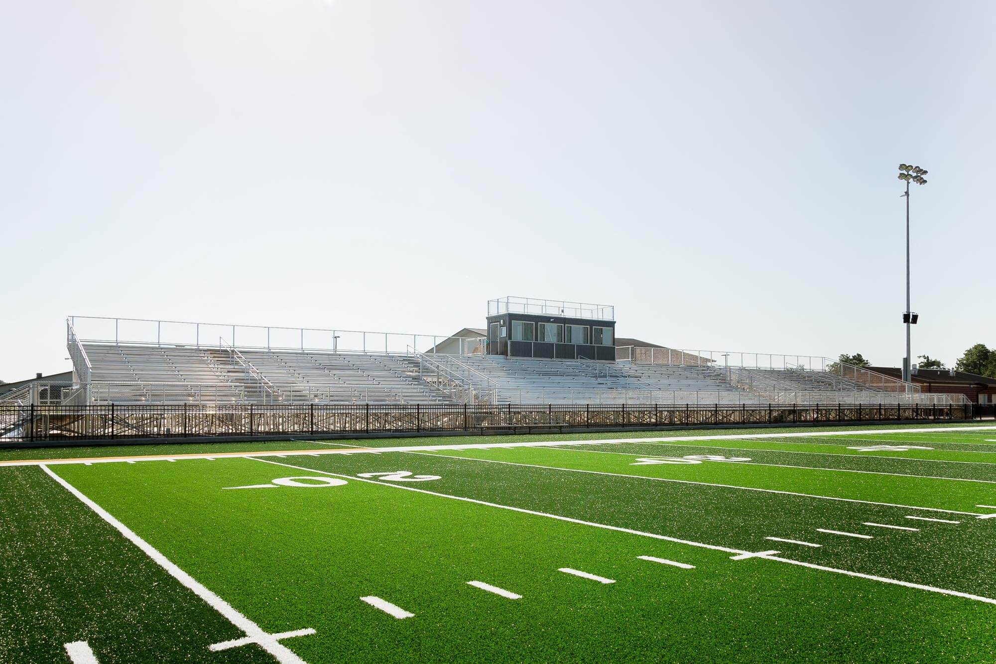 View of the visitor stands and press box from the field with light poles
