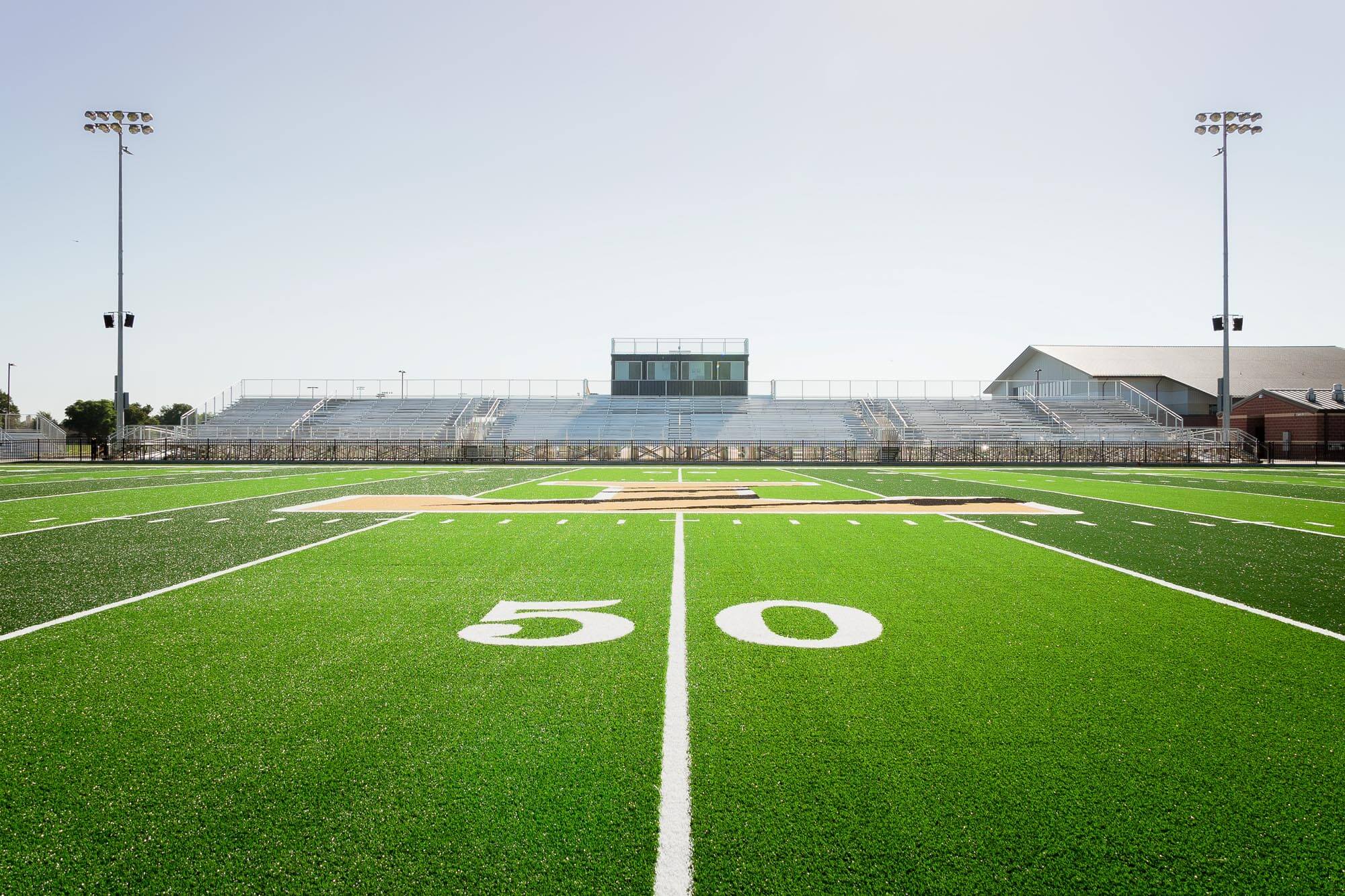 Centered 50-yard-line view with Wildcat logo, symmetrical bleachers and light poles
